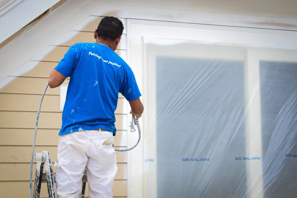 Painter spraying house siding